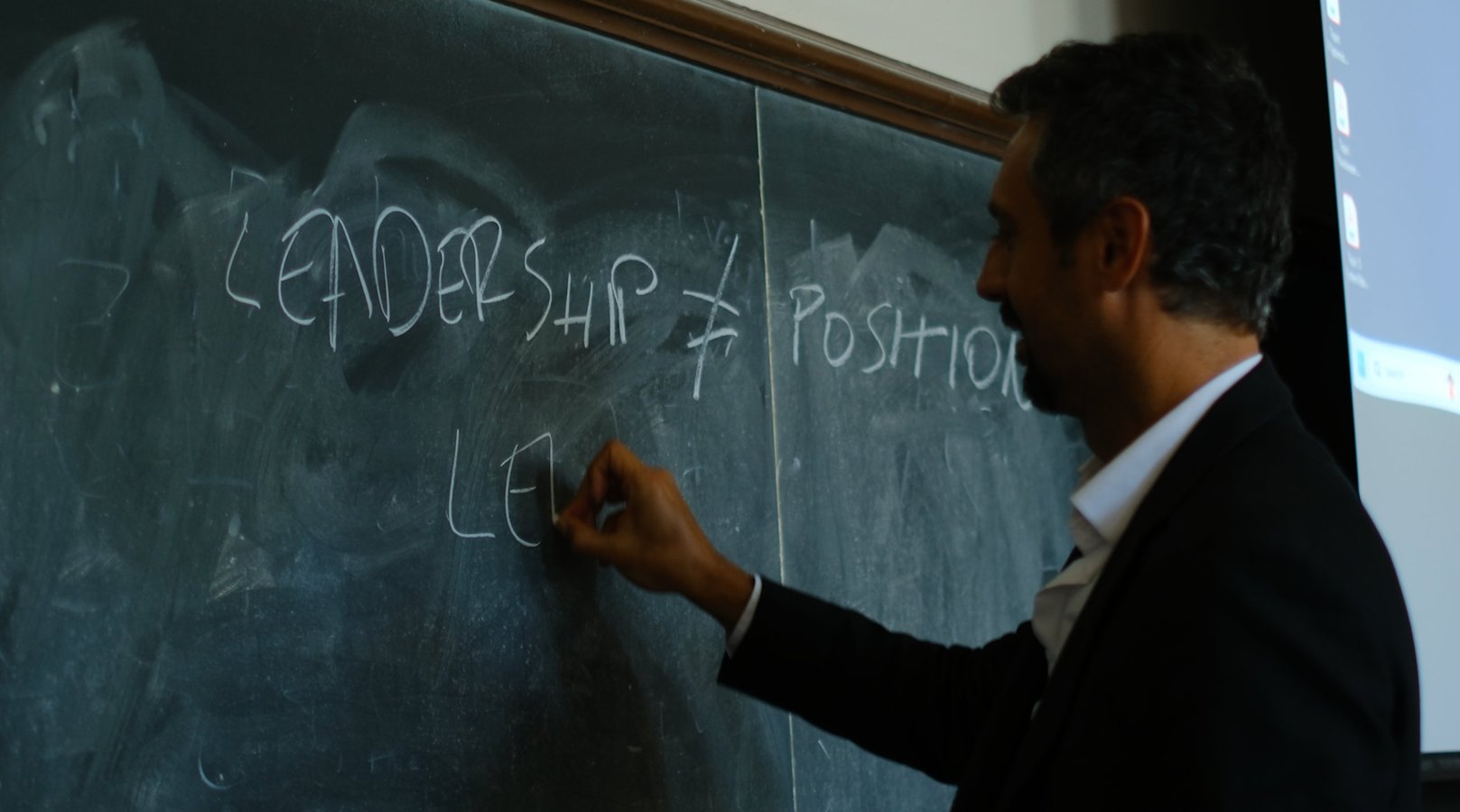 Nikola Ilić writing 'Leadership ≠ Position' on a chalkboard at Georgetown University